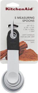 A set of five white plastic measuring spoons with the following approximate sizes: 1 tablespoon, 1/2 tablespoon, 1 teaspoon, 1/2 teaspoon, 1/4 teaspoon.