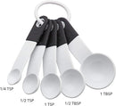 A set of five white plastic measuring spoons with the following approximate sizes: 1 tablespoon, 1/2 tablespoon, 1 teaspoon, 1/2 teaspoon, 1/4 teaspoon.