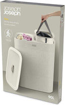 Joseph Joseph ecru 90-liter dual laundry hamper with removable fabric bags and lid, displayed on a white background.