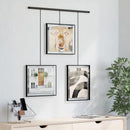 A modern black frame photo display featuring three frames suspended from a horizontal bar by thin rods.