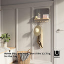 A sleek white wall-mounted organizer mirror with rounded corners, featuring a light wood shelf beneath it. Below the shelf, a white bar extends with several wooden peg hooks.