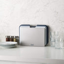 Compact set of three Joseph Joseph cutting boards with a space-saving design and metal handles.