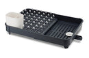 Joseph Joseph gray expandable dish drying rack with cutlery holder and drainboard set on a white background.