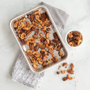 cashews and pecans in a Nordic Ware Prism eighth sheet baking pan with embossed grid pattern and silver aluminum finish on a white background