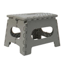 A grey plastic foldable step stool with a carrying handle. The top has an anti-slip pattern, and the stool is shown in its open, ready-to-use position.