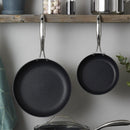 ScanPan fry pans hanging from a kitchen rack with other cookware