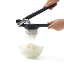 Pressing the potato ricer with freshly mashed potato falling into a bowl.