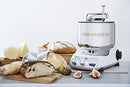 Premium Ankarsrum Original kitchen machine with a classic cream-colored base and large, polished stainless steel mixing bowl, ideal for baking and food preparation. This durable stand mixer features chrome accents and a front control panel with two dials for easy operation.