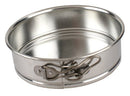 A shiny, round, silver-colored springform pan with a clasp mechanism on the side, likely for baking.