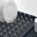 Joseph Joseph gray expandable dish drying rack with cutlery holder and drainboard set on a white background.