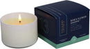 A burning, pale yellow candle in a white ceramic votive, positioned next to its dark blue and light green hexagonal packaging box. The box features the "TRAPP FRAGRANCES" logo and "BOB'S FLOWER SHOPPE™" with scent notes of "FRESH FLORALS, CUT GREEN STEMS, WATERY ACCORDS," and is labeled as "FRAGRANCED CANDLE 3.75 oz | 106g ℮" with the number "13" prominently displayed.