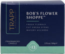 A top-down view of a dark blue and light green hexagonal box for a "TRAPP FRAGRANCES" candle. The box is prominently labeled "BOB'S FLOWER SHOPPE™" and lists scent notes as "FRESH FLORALS, CUT GREEN STEMS, WATERY ACCORDS." It is designated as a "FRAGRANCED CANDLE" weighing "3.75 oz | 106g ℮" and is identified as "No. 13".