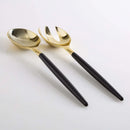 Black and gold plastic serving fork and spoon set displayed on a white background.