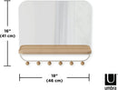 A sleek white wall-mounted organizer mirror with rounded corners, featuring a light wood shelf beneath it. Below the shelf, a white bar extends with several wooden peg hooks.