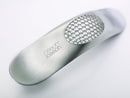 Joseph Joseph stainless steel garlic rocker crusher with curved design shown on a white background.