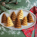 small fir tree cakelets, displayed on a white plate on a festive table.