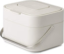 Joseph Joseph stone-colored compost bin with stainless-steel handle and flip-top lid shown on a white background.