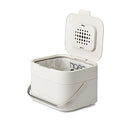 Joseph Joseph stone-colored compost bin with stainless-steel handle and flip-top lid shown on a white background.