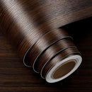 A tightly rolled coil of self-adhesive contact paper, displaying a rich, dark brown wood grain pattern with visible texture.