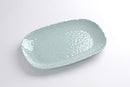 A Pampa Bay Capri Melamine Medium Serving Platter is shown on a white surface. The platter has a gently oblong shape and a light aqua blue color with a subtle hammered or textured appearance. The rim is decorated with a continuous row of small, raised beads.