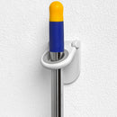 A close-up of a white Spectrum Diversified plastic mop and broom holder mounted on a textured white wall. A mop with a silver-colored pole, a blue grip, and a yellow cap is securely held in the gray rubberized grip of the holder.