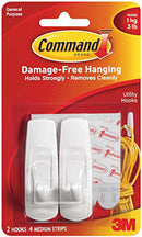 Retail packaging for 3M Command Brand Utility Hooks, containing two white, general-purpose hooks and four medium-sized adhesive strips for damage-free hanging. The packaging highlights that the hooks hold strongly and remove cleanly, supporting up to 1 kg (3 lbs).