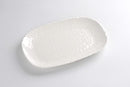 A Pampa Bay Waves Melamine Medium Serving Platter is shown on a white surface. The platter has a gently oblong shape and an off-white color with a textured surface that resembles subtle waves or ripples. The rim is decorated with a continuous row of small, raised beads.