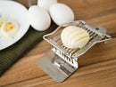 A silver-toned Fox Run egg slicer with wires stretched across a cradle. A hinged top with additional slicing wires is lifted open. A base plate extends from the bottom.
