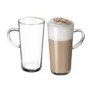 This is a set of two tall, clear glass latte mugs, each featuring a sturdy, curved handle and a sleek, slightly tapered cylindrical shape with a thick, durable base. One mug is empty, highlighting its transparent design, while the other holds a creamy, layered latte topped with thick milk foam and a dusting of cocoa or cinnamon. These mugs are perfect for serving hot beverages like lattes, cappuccinos, or hot chocolate.