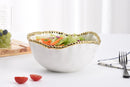 Elegant white ceramic bowl with a wavy rim and gold beaded edge detailing.
