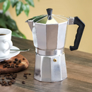 Grey 9-cup aluminum stovetop espresso maker with an octagonal body and black handle, shown on a table
