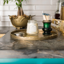 A small, cream-colored candle from Greenleaf, in the Bella Freesia fragrance, presented in a clear jar with a silver lid.