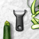 OXO Black peeler on a marble countertop with peeled vegetable