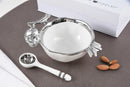 Silver pomegranate-themed bowl and spoon set with titanium finish, elegantly displayed on a table
