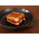 Black cast iron grill pan with raised parallel ridges on the cooking surface and a long handle extending to the right.