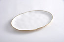 A Pampa Bay Moonlight Oval Platter is shown on a white surface. The platter has an elongated, somewhat irregular oval shape and a smooth, glossy white finish. A thin, delicate gold rim outlines the edge of the platter.