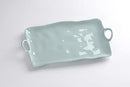 A Pampa Bay Melamine Aqua Large Platter is shown on a white surface. The platter is a soft, light blue color with a slightly uneven, organic shape and raised edges. It features integrated circular handles on both shorter ends. The platter has a subtle sheen, indicating it's made of melamine.